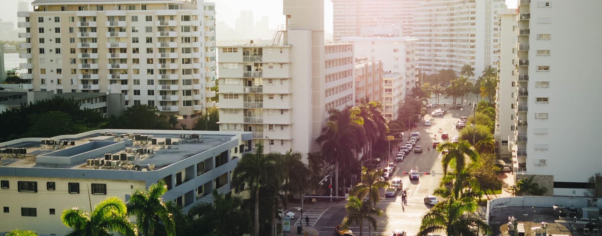 aerial view of white apartment buildings and streets lined by palm treea